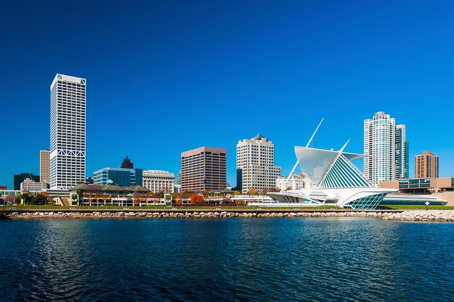 Milwaukee city skyline with modern and historic buildings, including the Milwaukee Art Museum, viewed from across the water on a clear day.